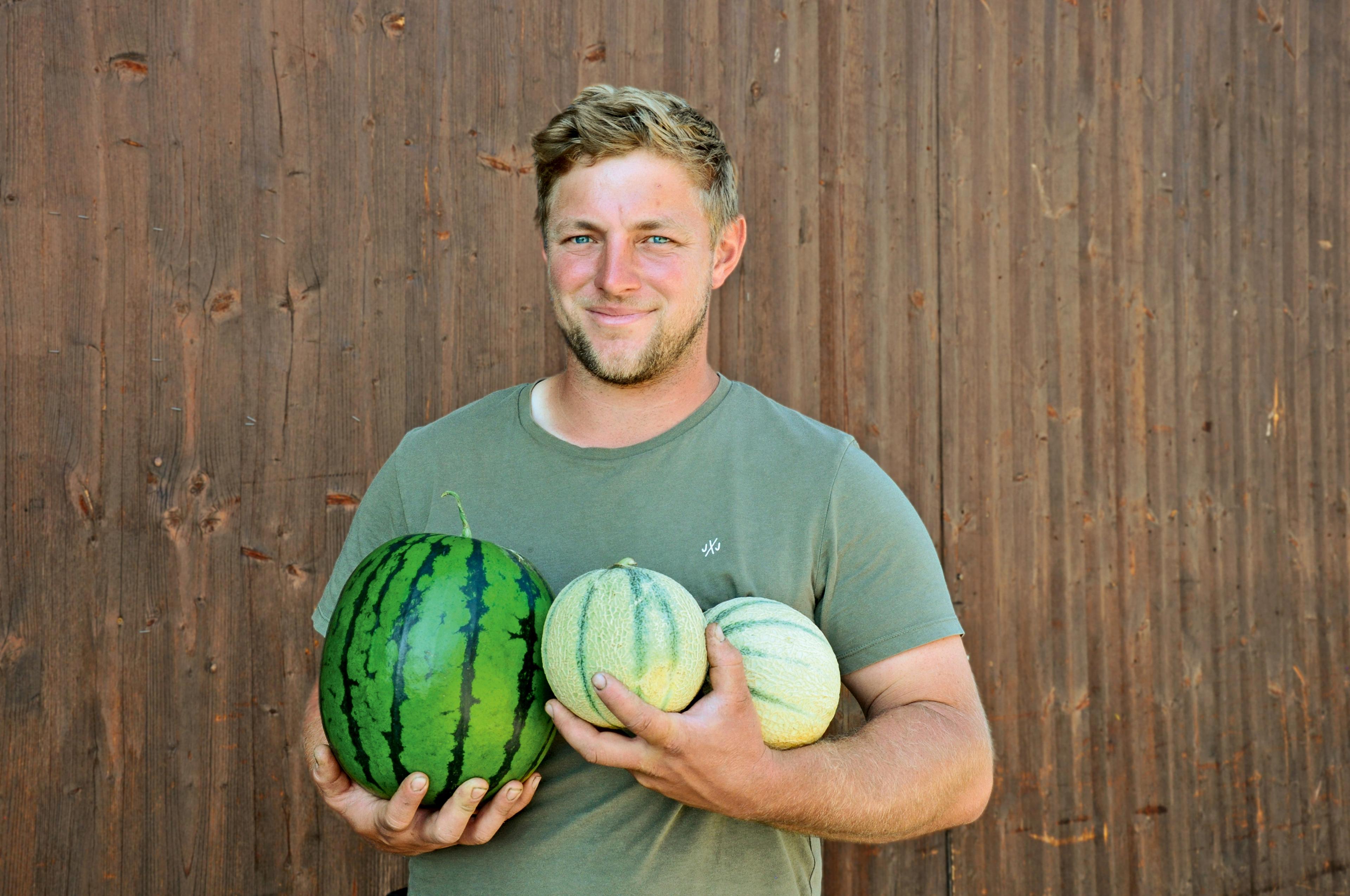 Daniel Wilhalm hält eine Wassermelone und zwei Honigmelonen in den Händen