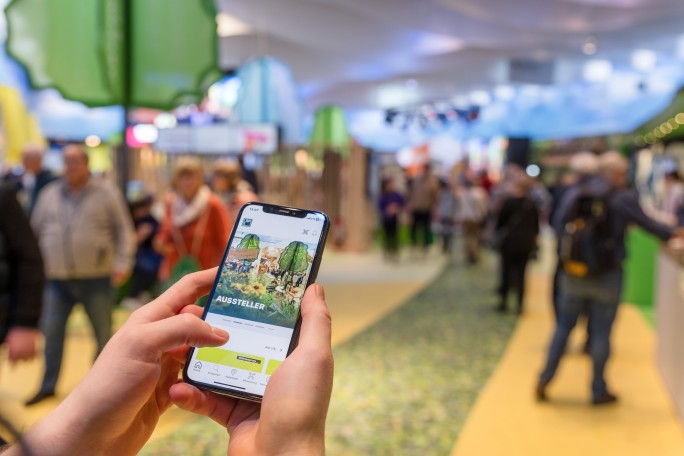 A cell phone in front of a blurred background, on whose display the hall plan of Grüne Woche can be seen.