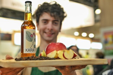 Mann präsentiert auf einem Tablett geschnittenen Apfel und eine Saftflasche